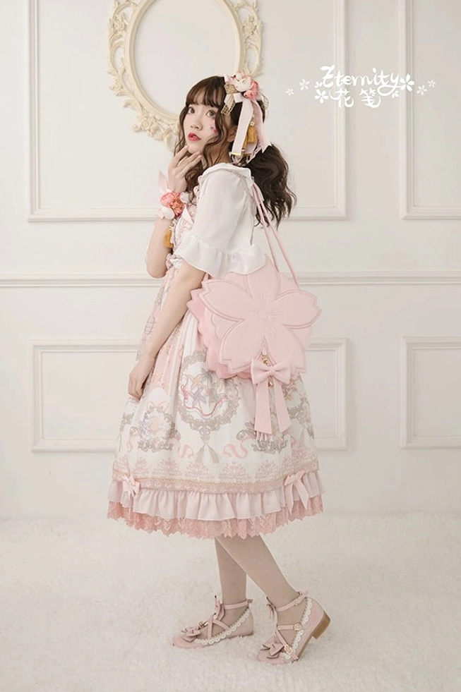 Pink sakura petal lolita handbag worn crossbody on shoulder with ruffled skirt hem and vintage print dress detail