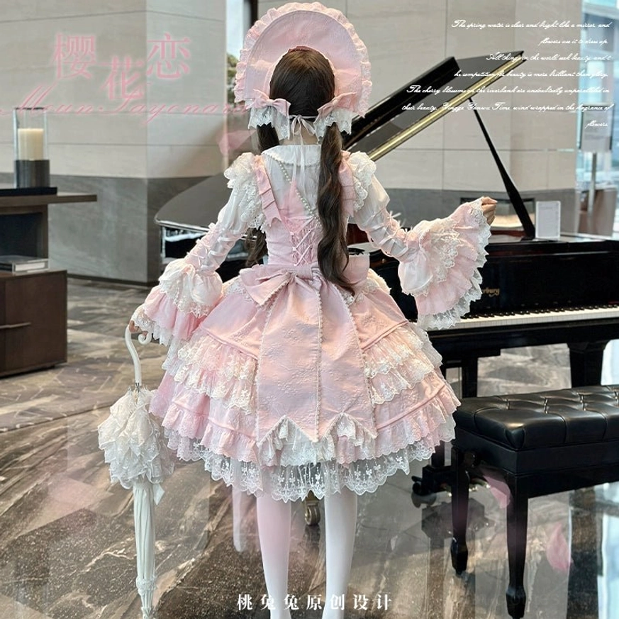 Back view of pink Sakura Love lolita dress suit with large decorative back bow, tiered satin and lace skirt, long puff sleeves, matching pink bonnet, holding lace parasol at grand piano