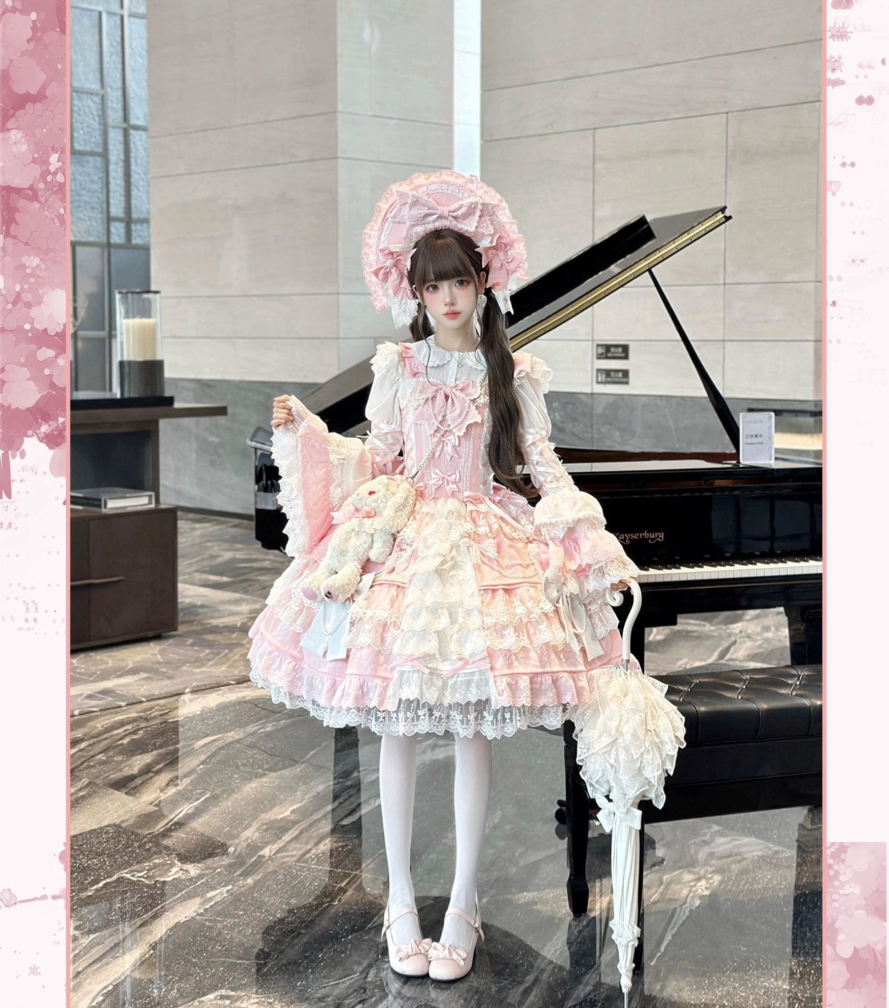 Full front body view of pink Sakura Love lolita dress suit with tiered ruffle lace skirt, white knee-high socks, bow shoes, matching bonnet and accessory, grand piano studio background