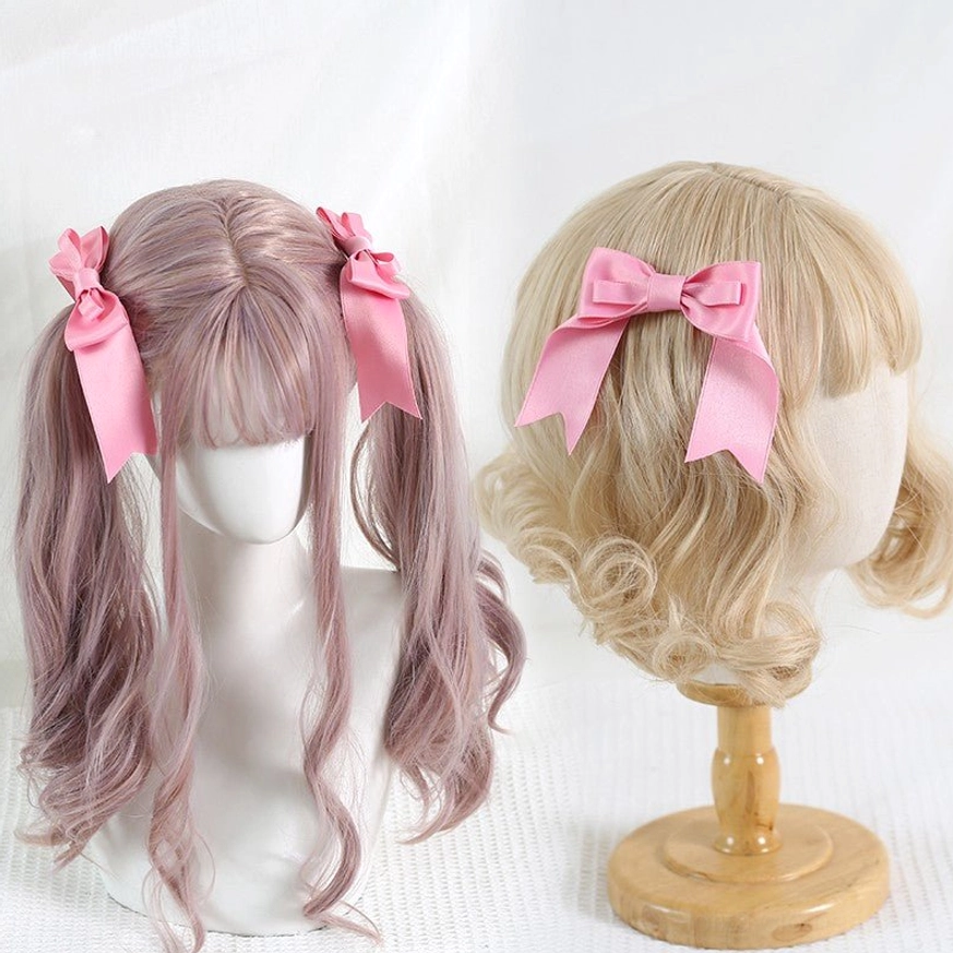Pink satin bow hair clips styled on light purple and blonde curly wig mannequins demonstrating twin pigtail hairstyle for classic lolita fashion