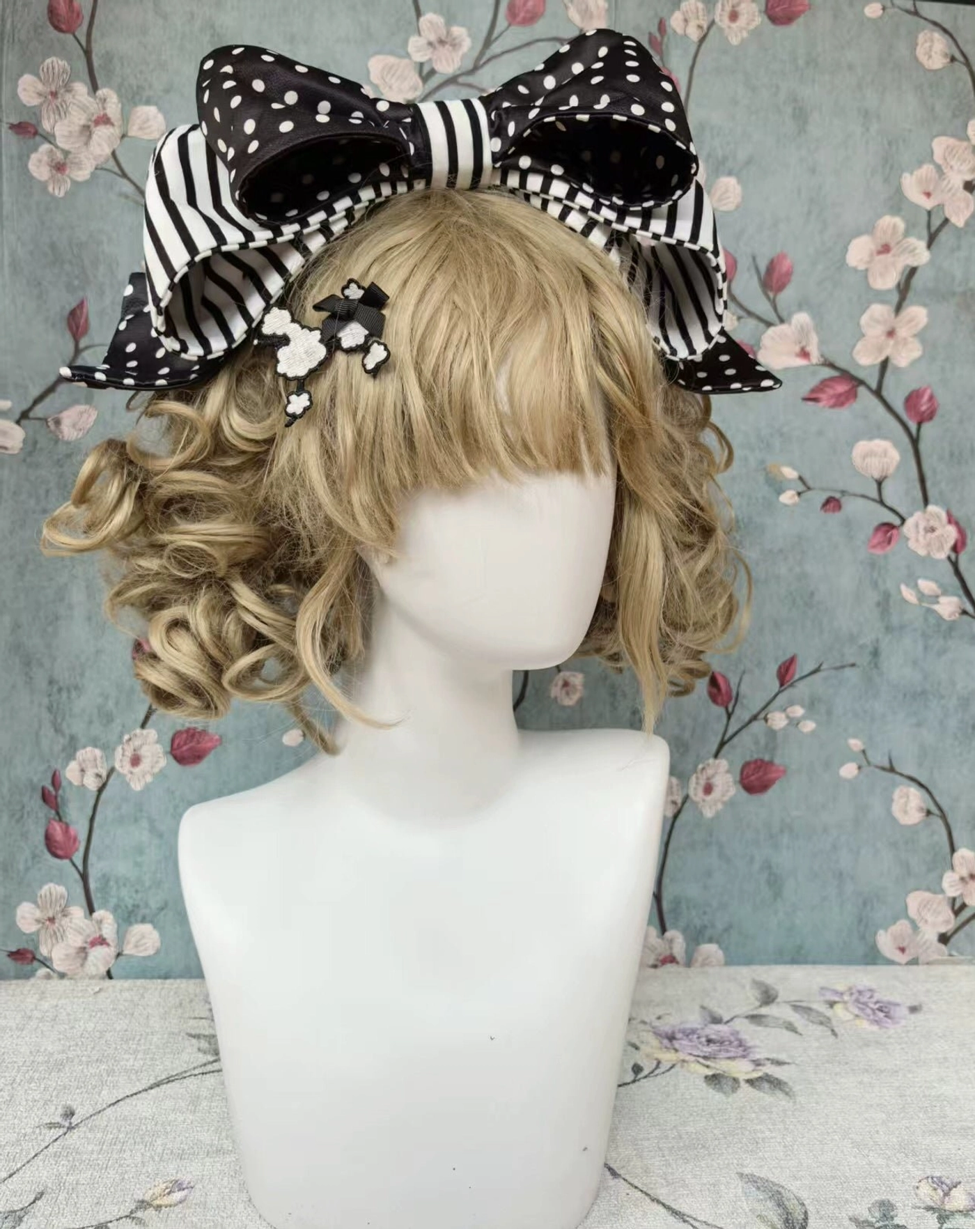 Pink striped lolita KC headbow with large double-layer bow design and small pink flower hair clips on blonde curly wig for complete lolita coordinate