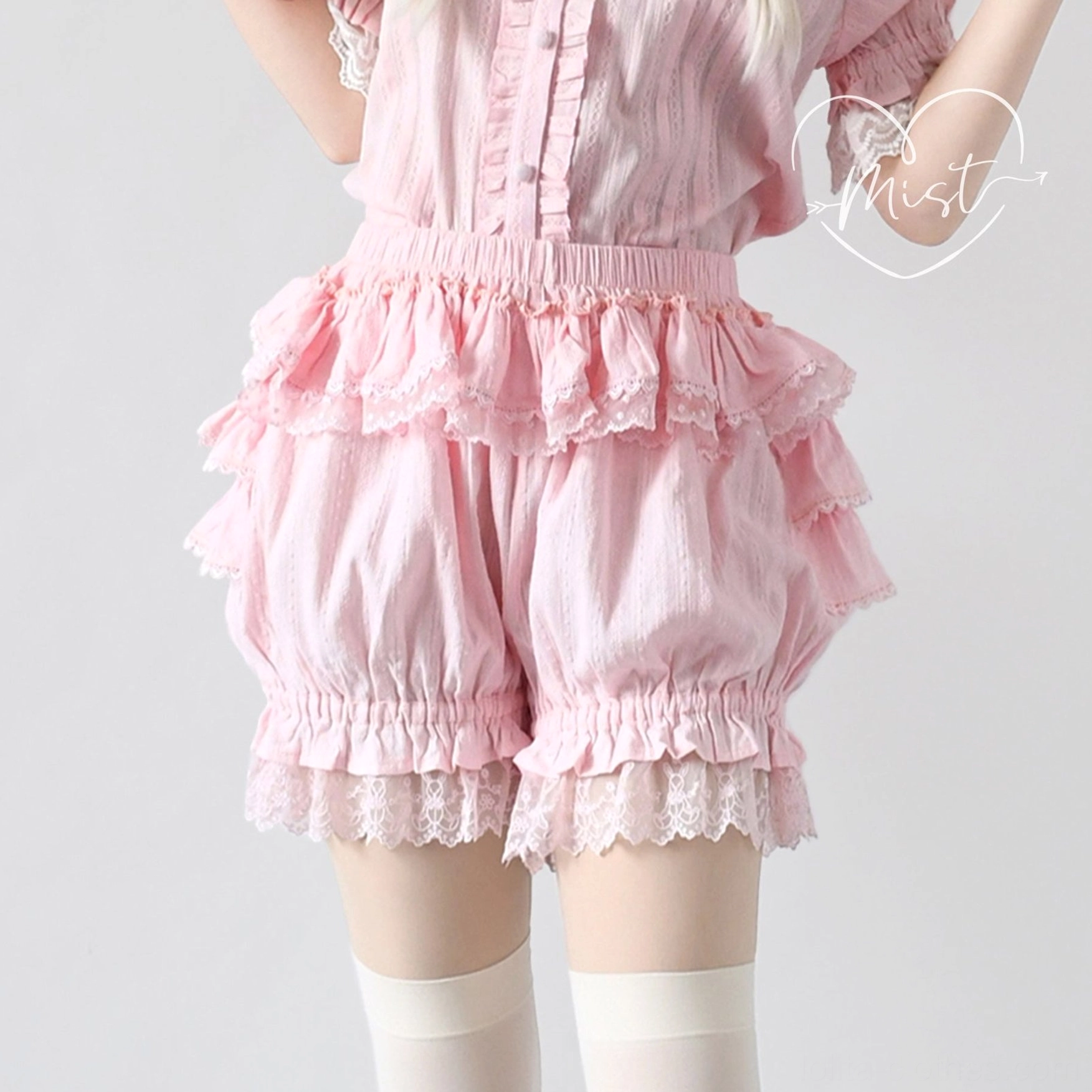 Pink lolita bloomer shorts front close-up with model wearing white thigh-high stockings, featuring ruffled waistband, multi-layered ruffles, delicate lace hem, and matching pink top