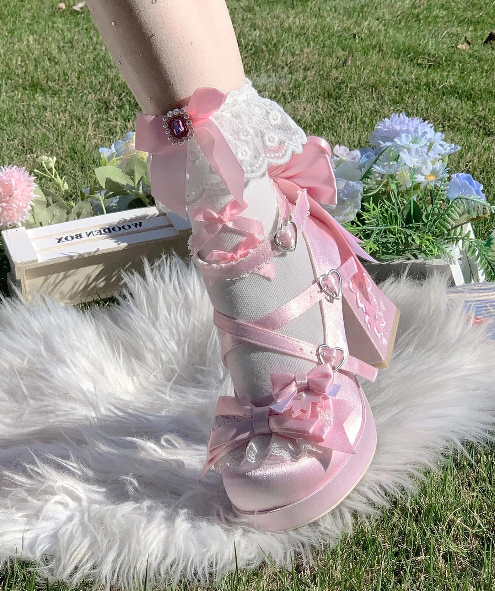 Pink sweet lolita chunky platform heel shoes with ribbon bows lace trims ankle gem decorations and heart buckles worn on fur rug with floral background outdoor