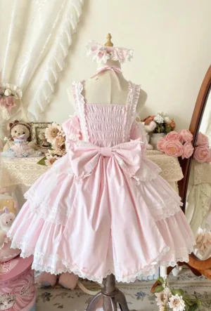 Pink Sweet Lolita jumper skirt back view on dress form showcasing shirred back panel decorative waist bow lace-trimmed tiered skirt floral roses plush toys