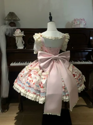 Back view of pink sweet lolita JSK dress showing detachable oversized satin bow, wide adjustable shoulder straps, frilled skirt hem, and matching bunny cake print fabric