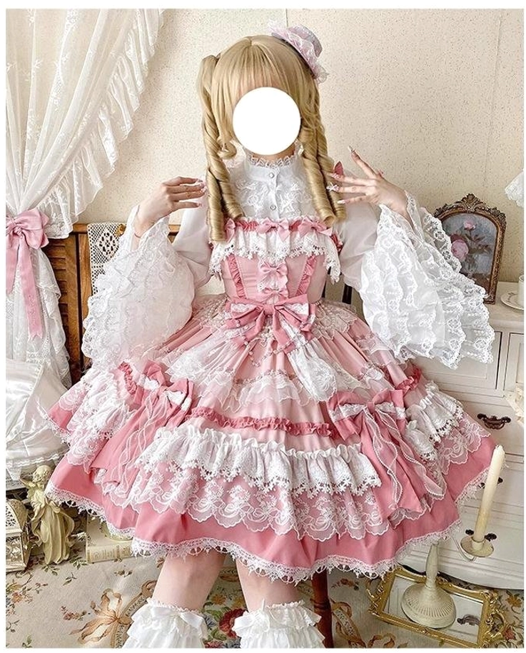 Front close-up of pink lolita jumper dress showing puff lace sleeves, layered lace skirt hem, front waist decorative bow on model adjusting shoulder straps