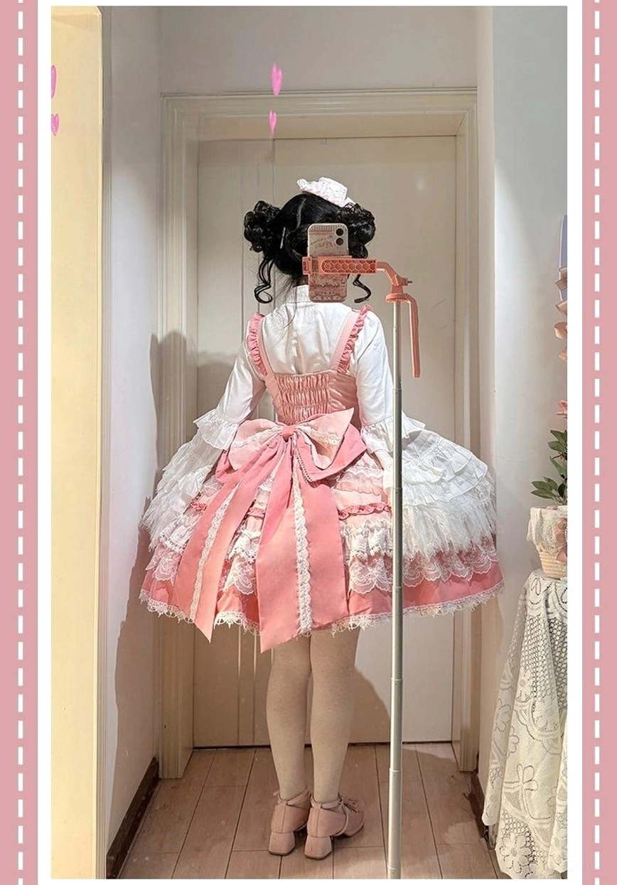 Pink sweet lolita JSK dress styled flat-lay overhead view with coordinating accessories including hair bows, pearl necklace, and white lace socks for complete outfit