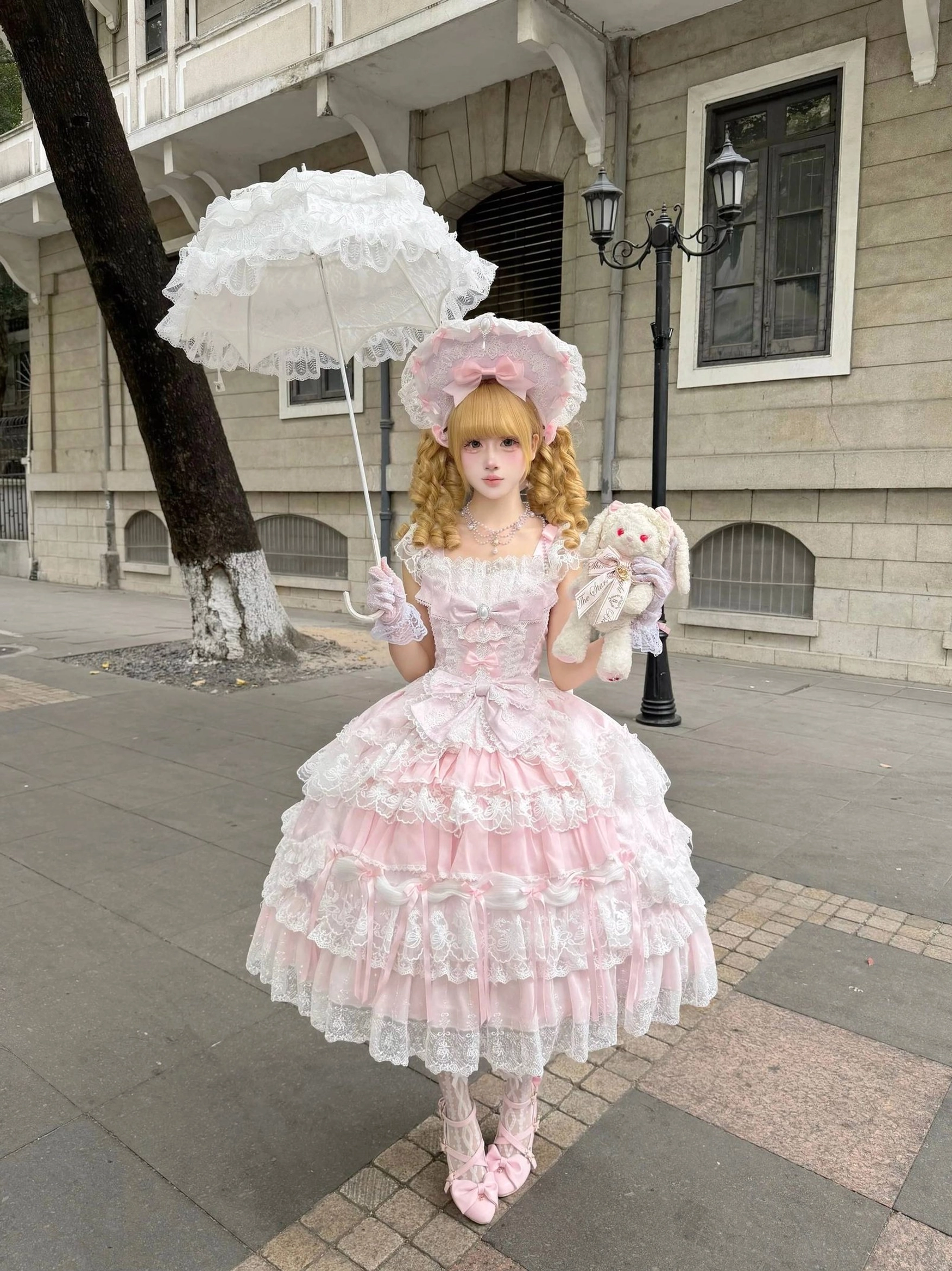 Front and angle view of pink sweet lolita tiered JSK dress showing square neckline layered ruffles and romantic silhouette
