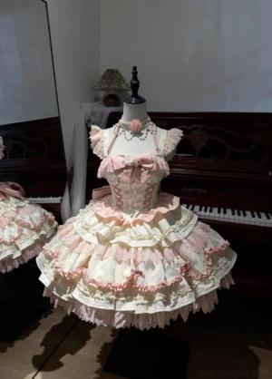 Pink sweet lolita jumper skirt with white lace tiered skirt front view on display mannequin halter neckline floral pearl chain choker accent detachable bow