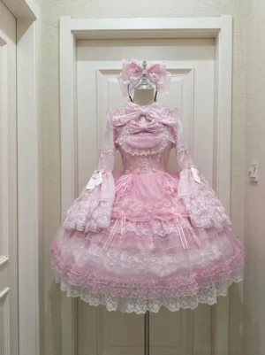 Pink sweet lolita chiffon jumper skirt JSK with tiered ruffled layers lace trims and oversized bow necklace displayed on door hanger full front view