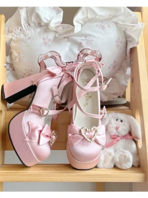 Pink Sweet Lolita heart themed Mary Jane heels with bow front view on wooden shelf with decorative heart pillow and plush accessories