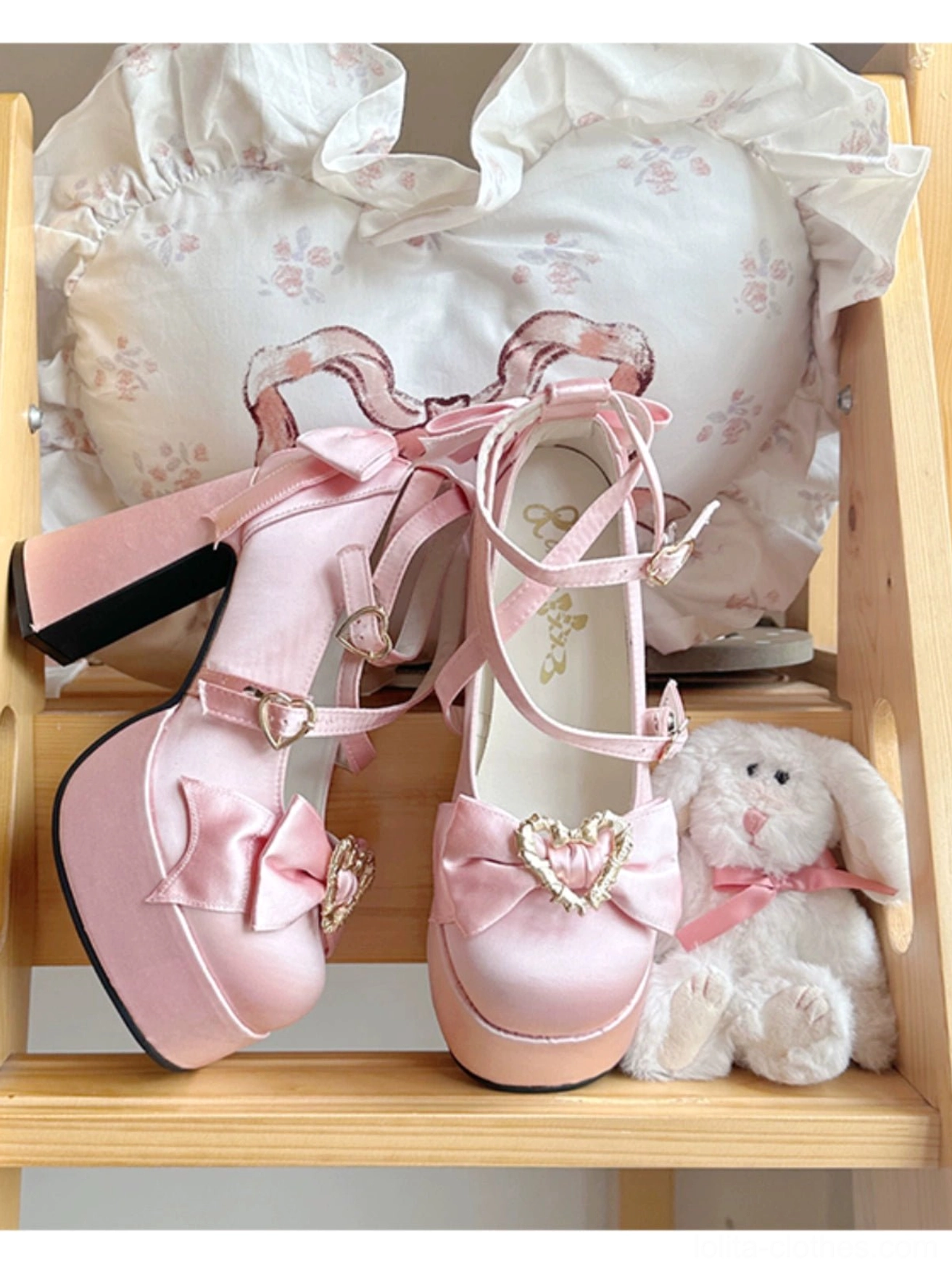 Pink Sweet Lolita heart themed Mary Jane heels with bow front view on wooden shelf with decorative heart pillow and plush accessories