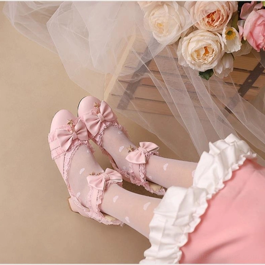 Overhead view of pink Sweet Lolita Mary Jane shoes showing multiple decorative bows with star charms and ruffled lace trim on model feet