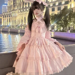 Pink sweet lolita one-piece dress featuring cross halterneck design with front bow, lace-trimmed tiered skirt, detachable puff sleeves, worn by model at twilight riverside urban setting