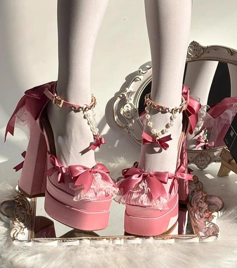Pair of pink sweet lolita platform heels with matching satin bows and pearl embellishments on fur mat display, thick platform chunky high heels