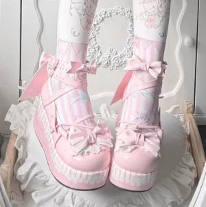 Pink sweet lolita platform Mary Jane shoes with decorative bows and lace details, showcasing rounded toe design and thick wedge sole on ruffled vanity setup with cartoon thigh highs