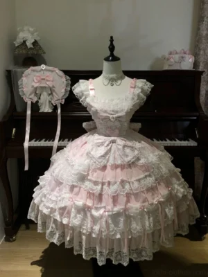 Front view of pink sweet lolita tiered JSK dress with square ruffled neckline and multi-layered lace skirt worn on mannequin in vintage studio setting