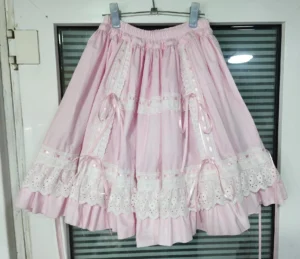 Pink sweet lolita underskirt displayed on hanger featuring soft pink cotton fabric with white eyelet lace trim and coordinating pink satin bows front view