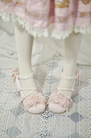Pink patent leather sweet Lolita wedding heels worn on model's feet with ruffled Lolita skirt and fishnet stockings, overhead first-person view showing 3D flower toe decoration
