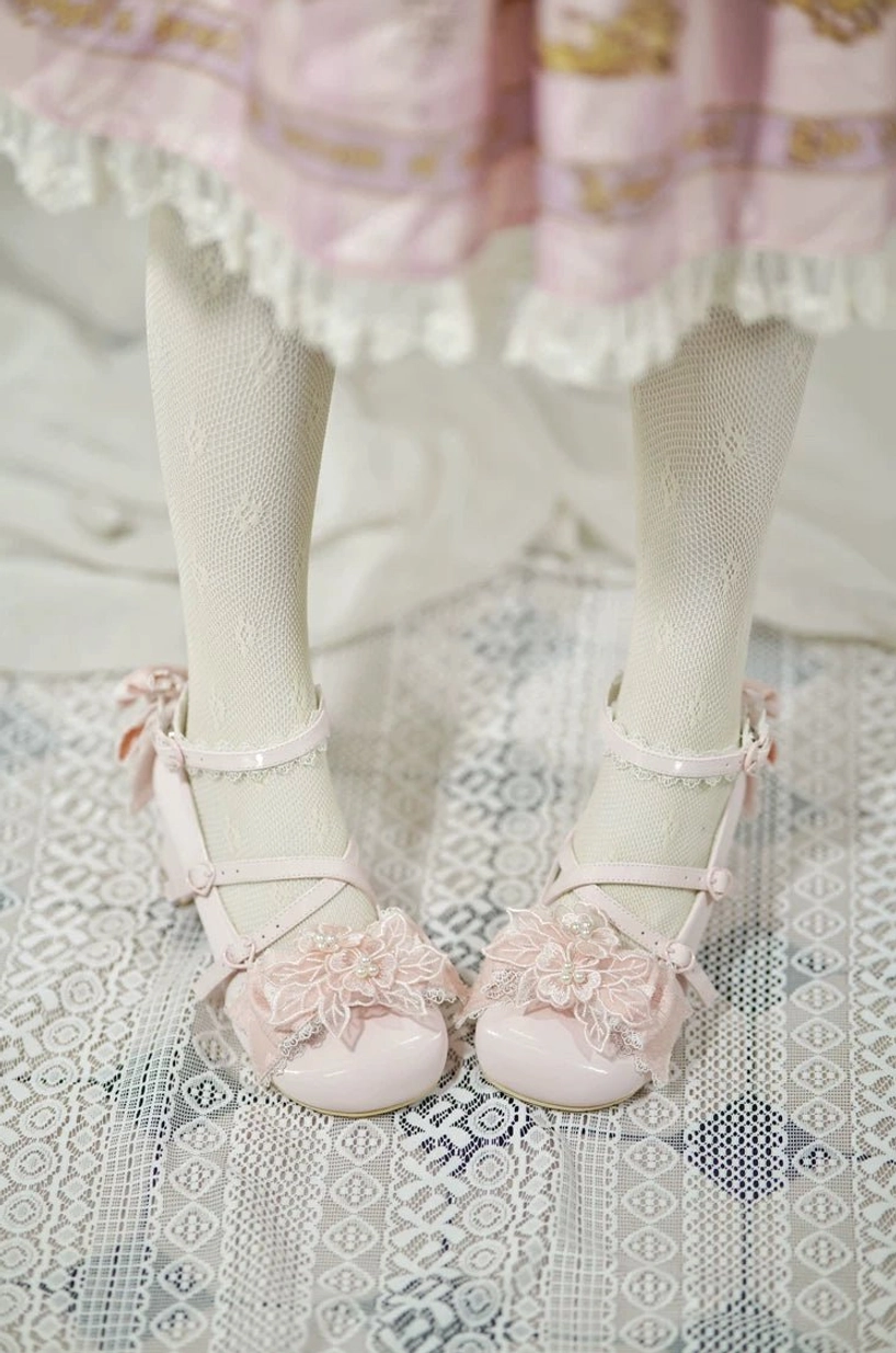 Pink patent leather sweet Lolita wedding heels worn on model's feet with ruffled Lolita skirt and fishnet stockings, overhead first-person view showing 3D flower toe decoration