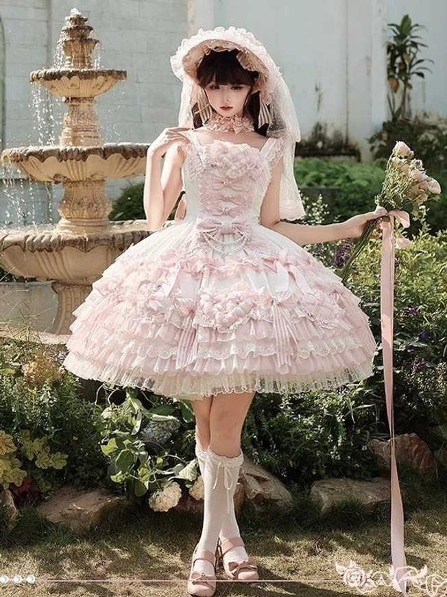 Pink sweet lolita wedding JSK dress full-body front view outdoor garden setting with stone fountain white ruffled lace skirt square neckline bridal veil bonnet