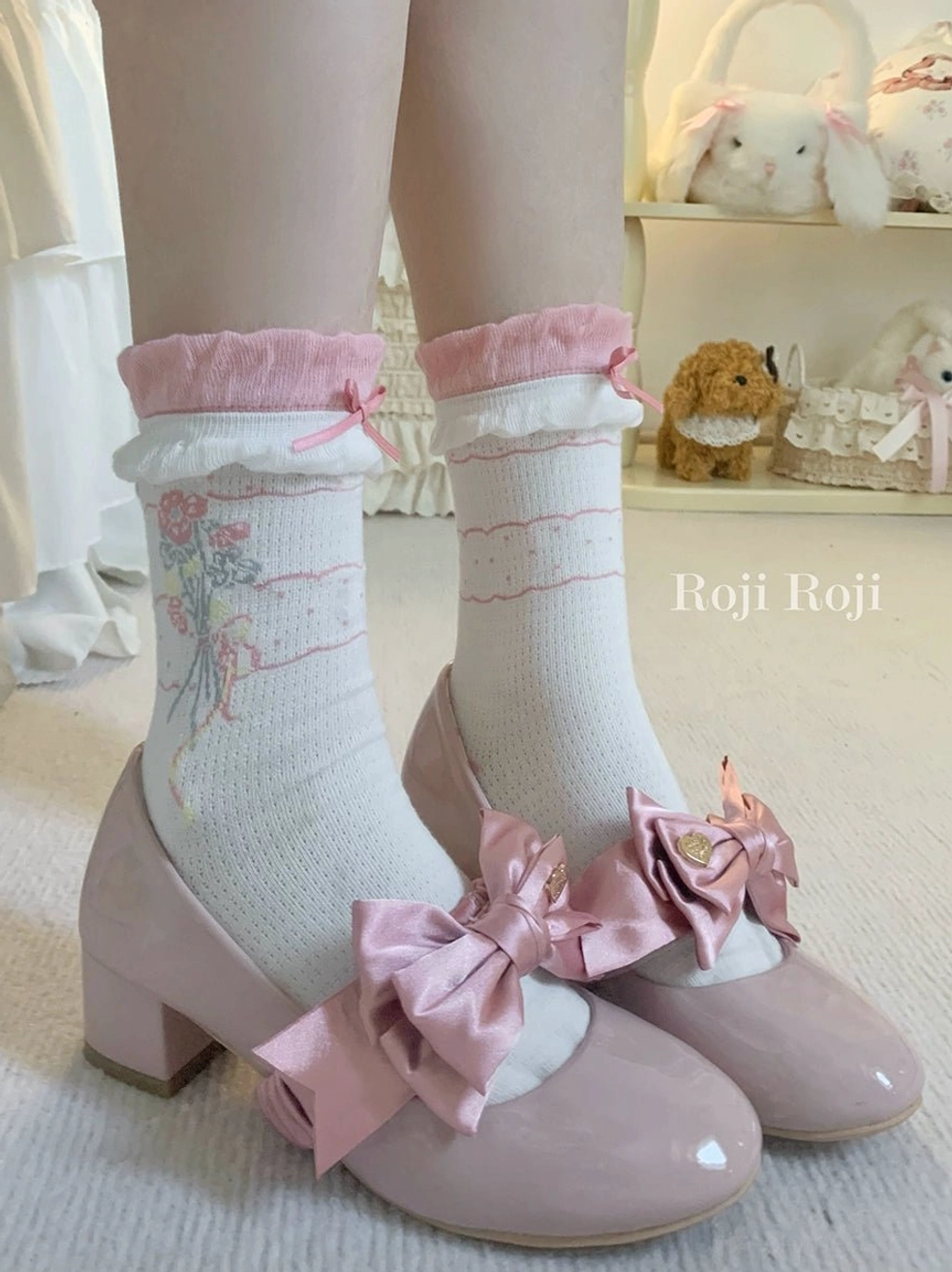 Pink lolita ankle socks with pink ruffled cuffs and delicate floral bouquet print paired with pink patent leather bow Mary Jane heels low angle standing feet view