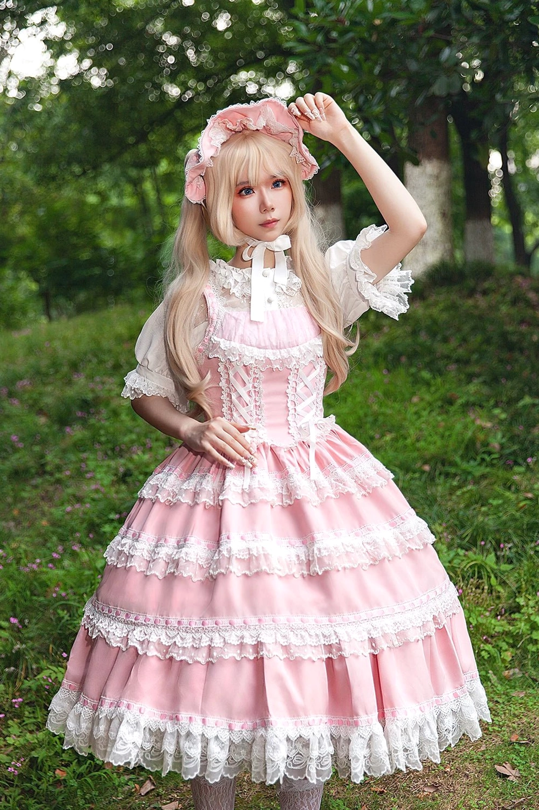 Full length model photo of pink vintage lolita JSK with matching pink bonnet and white ruffled neck blouse in grassy forest