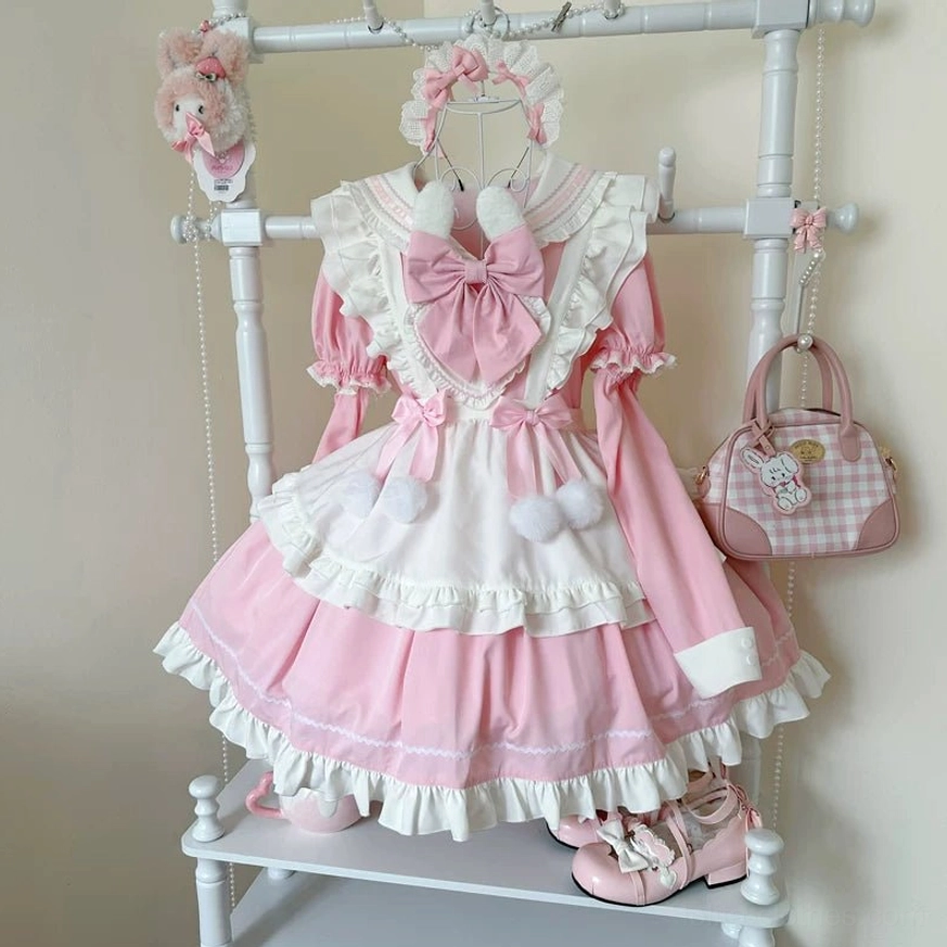 Pink and white maid lolita OP dress on clothing rack with big pink collar bow, frilly detachable apron, tiered ruffled skirt, pom-pom trims, matching pink handbag, front rack display