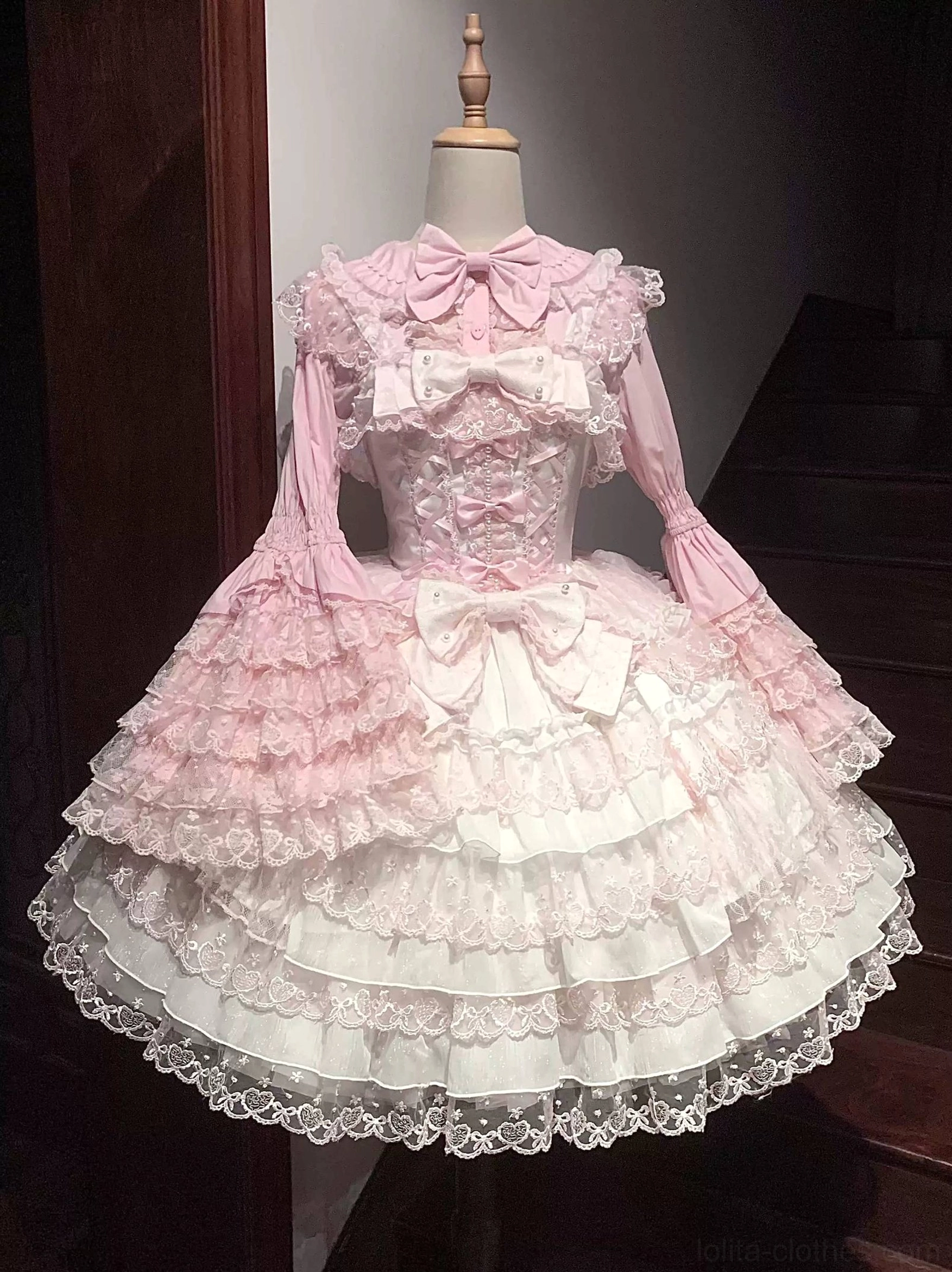 Pink-white Sweet Lolita JSK dress on dress form studio display front full-body shot showing tiered lace skirt, multiple front bows, square neckline, and flared lace sleeves