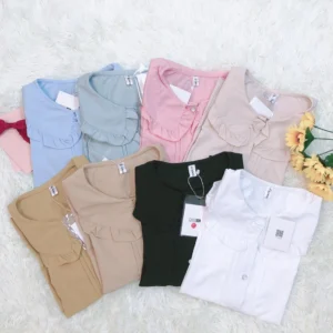 Flat lay overhead view of plus-size lolita short sleeve blouses in multiple colors including walnut black ivory light blue light pink and light green featuring peter pan doll collar and ruffled cuffs displayed on white fuzzy fabric