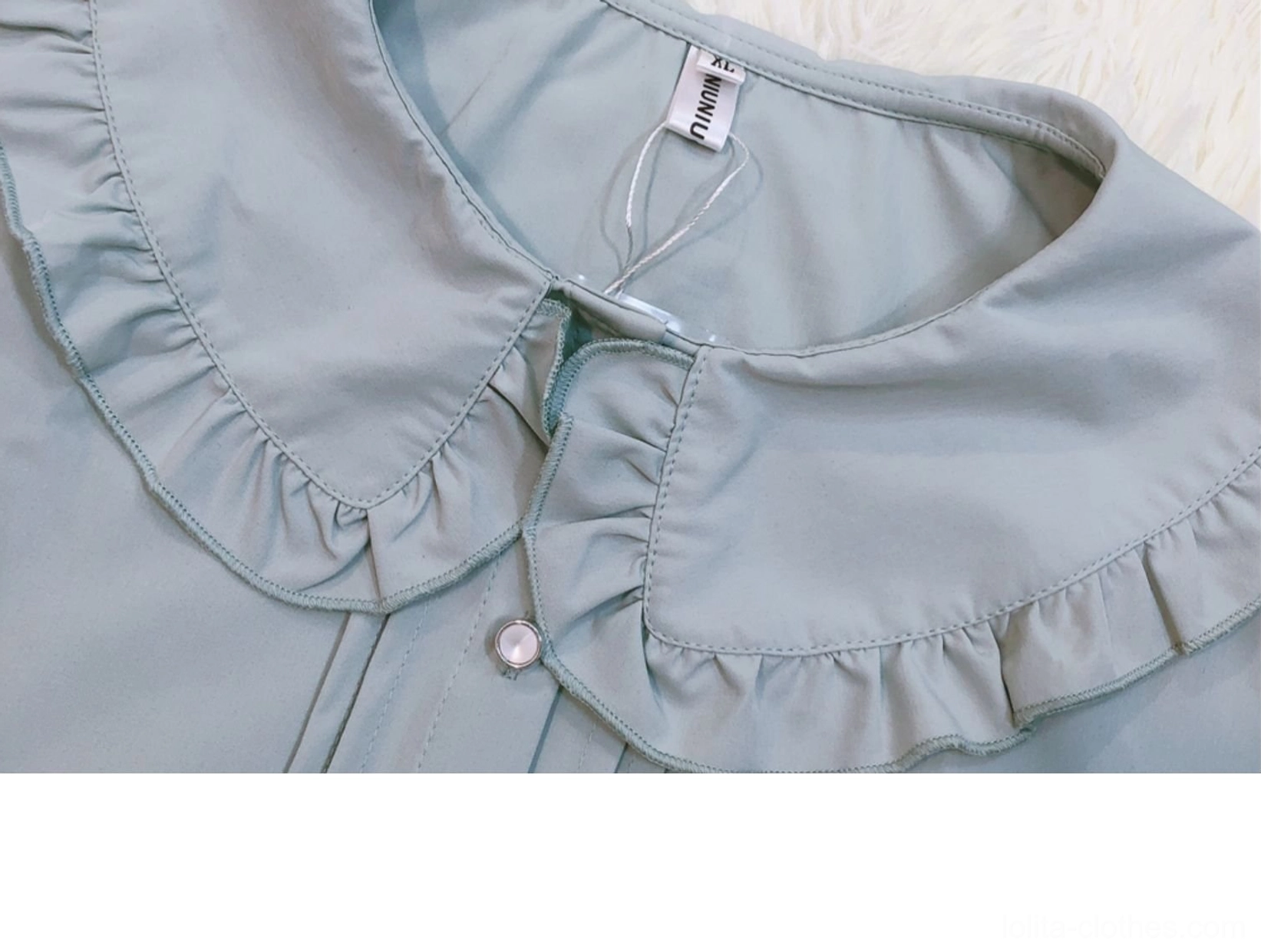 Close-up detailed view of smoky blue lolita blouse peter pan doll collar showing ruffled edge construction front button placket and premium sewing workmanship on flat lay display