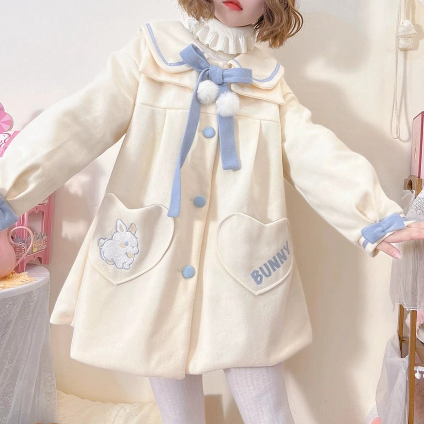 Plus size sweet lolita wool coat side three-quarter view with model arm pose showing A-line silhouette blue cuff trims loose hem and back heart-shaped pockets in cream off-white