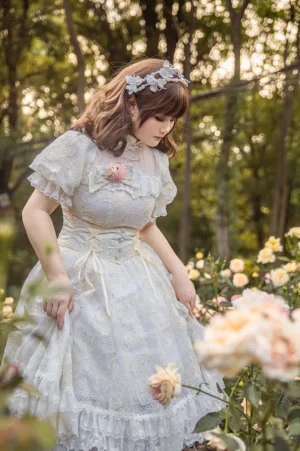 Plus size model wearing red lolita waist corset with white lace trim over romantic lolita dress in sunlit rose garden setting