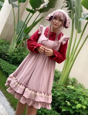 Full body plus size sweet Lolita coordinate featuring burgundy ruffled collar blouse with pink tiered ruffled pinafore outfit on model with bunny ear hair accessory in garden setting