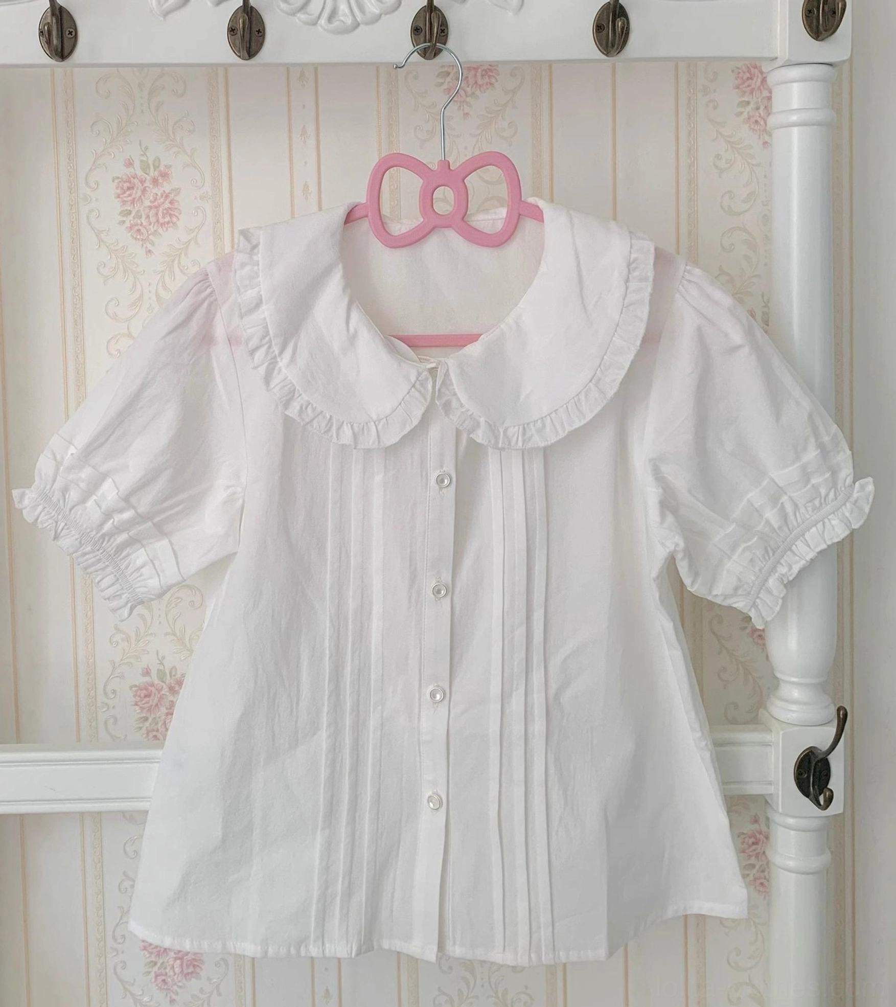 Plus size white cotton lolita blouse with peter pan collar and detachable ruffled princess sleeves displayed on pink bow hanger, front view showing pintuck details and round button placket
