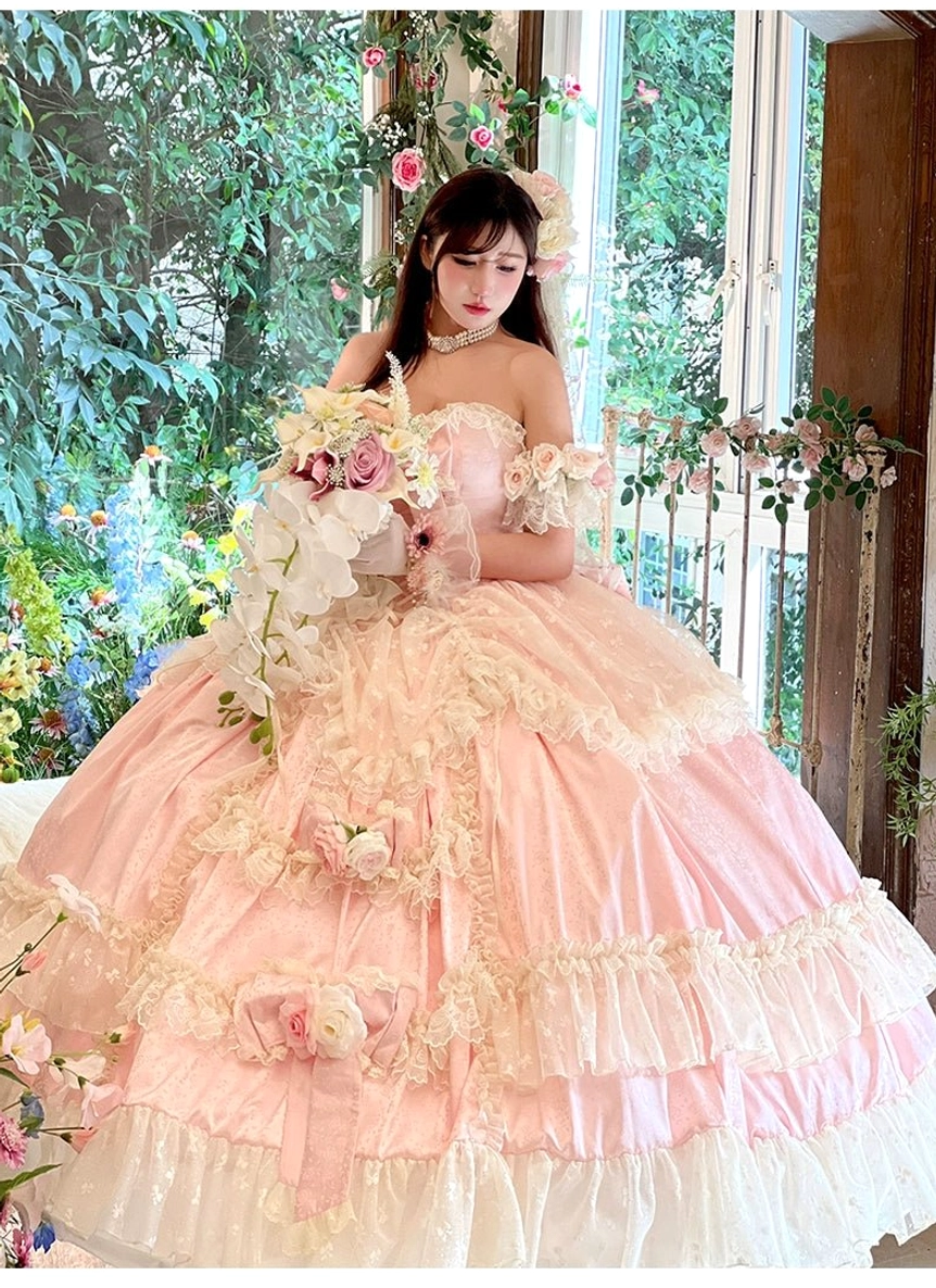 Three-quarter front shot of pastel pink princess bridal lolita gown with floral rose decorations and ruffled ball skirt