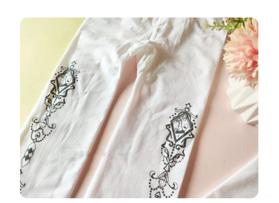 Flat lay side view of printed white Lolita pantyhose leg sections displaying detailed black vintage diamond and vine pattern on sheer white base