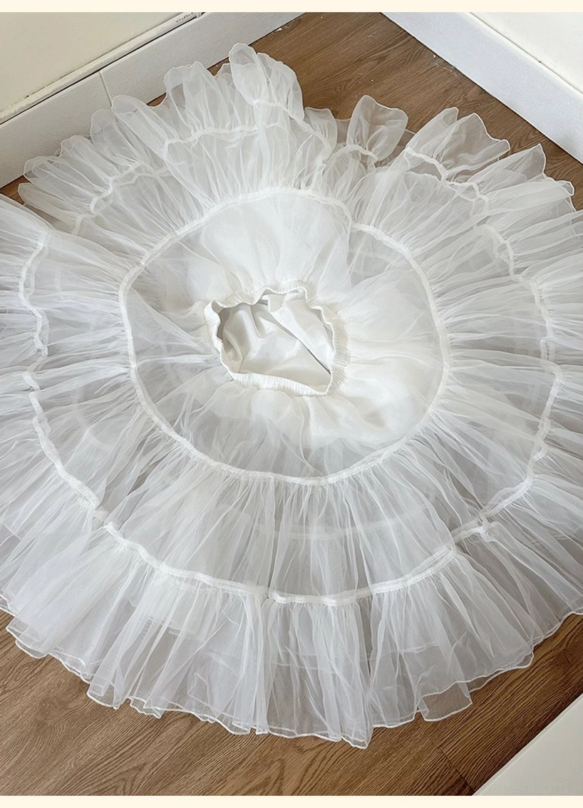 Puffy lolita petticoat flat lay overhead view on wooden table displaying wider fuller circular tulle layers with thick tiered ruffled design