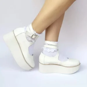 Side three-quarter view of punk lolita high platform ankle strap shoes worn with white frilled socks, showing off-white smooth leather upper and thick platform sole