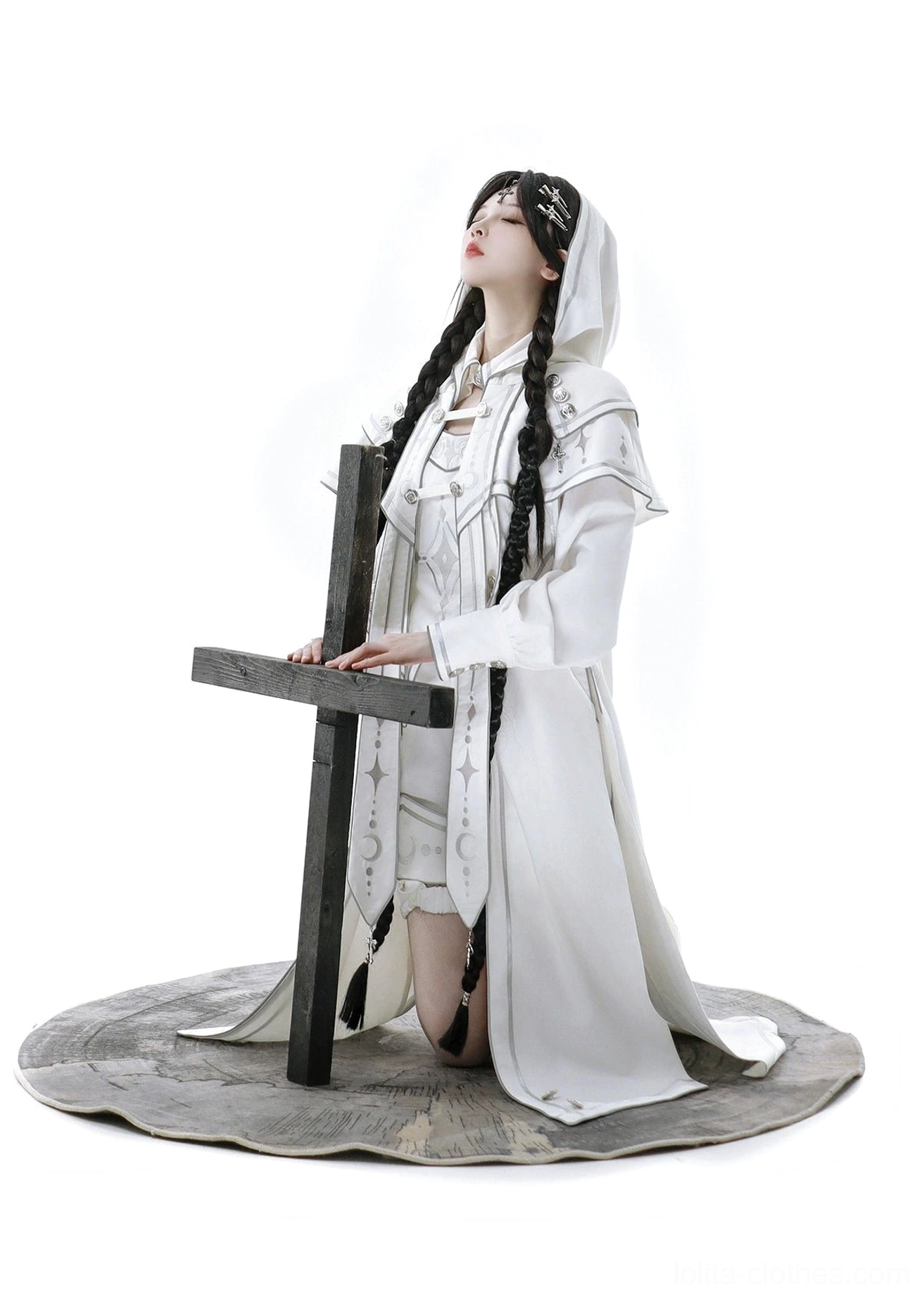 Kneeling pose of ethereal white lolita outfit showing hood up detail, front embroidery with four-pointed stars and moon motifs, high-neck collar, and buttoned cuffs on top
