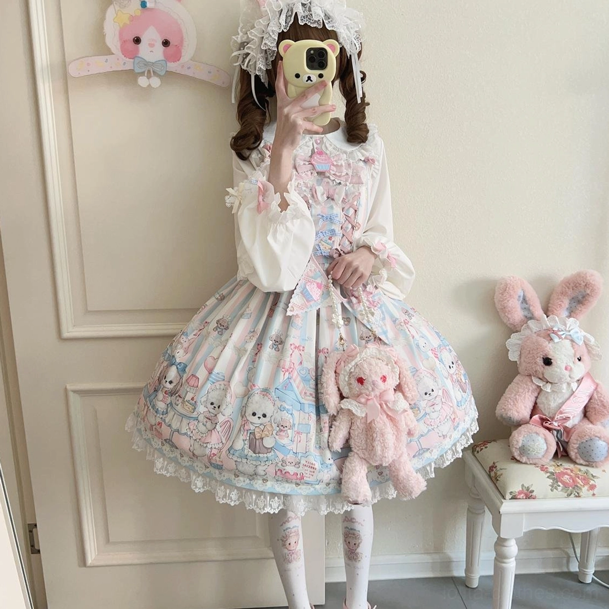 Lolita girl holding large pink rabbit plush toy while wearing puppy print JSK jumper skirt and matching sash, front mirror selfie view showcasing sweet Lolita fashion aesthetic and styling