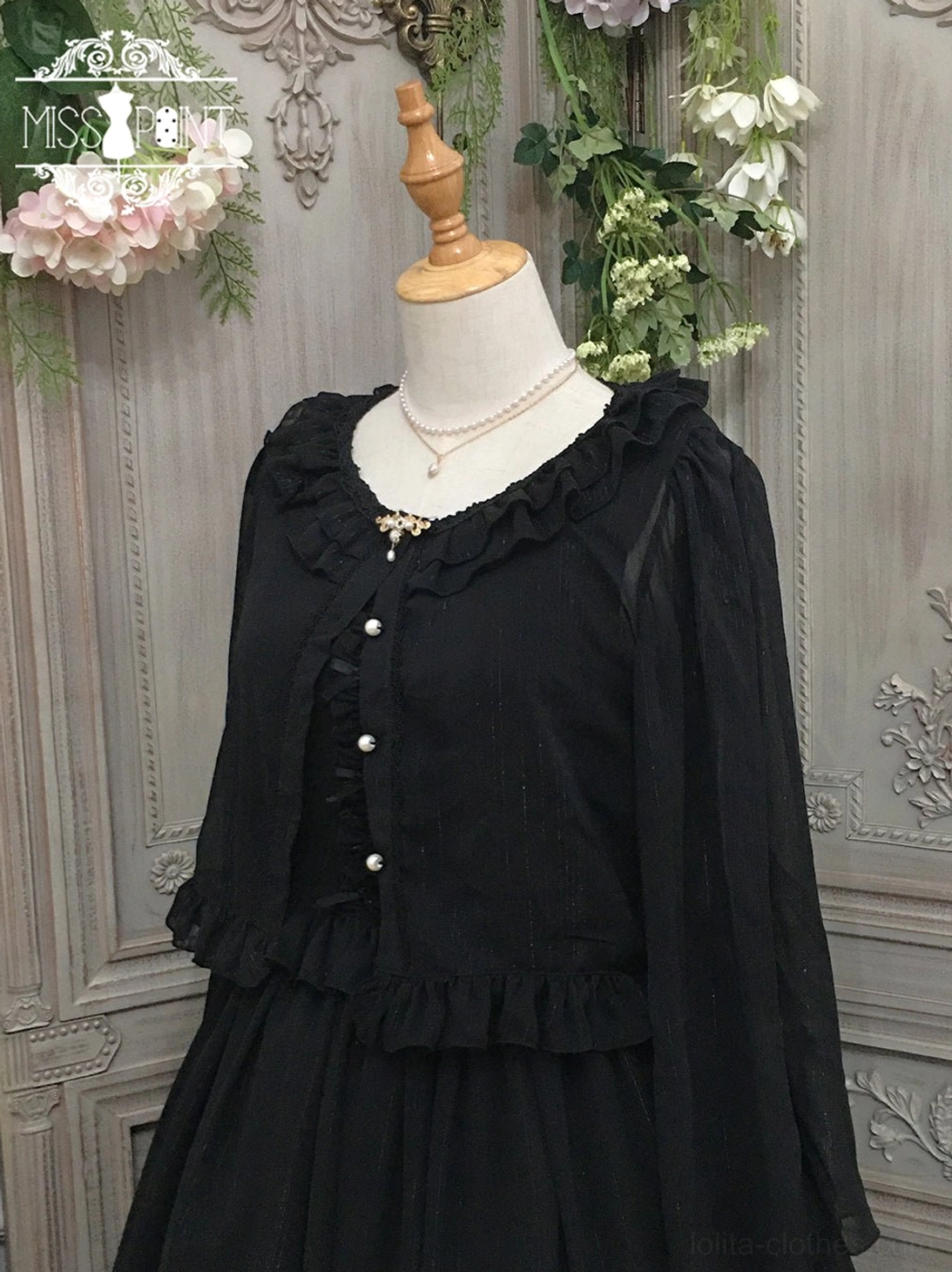 Pure black lolita cardigan featuring ruffled crew neckline and shoulders, pearl button front closure, ruffled waist trim, crafted in sheer chiffon, displayed on dress form against vintage ornamental backdrop