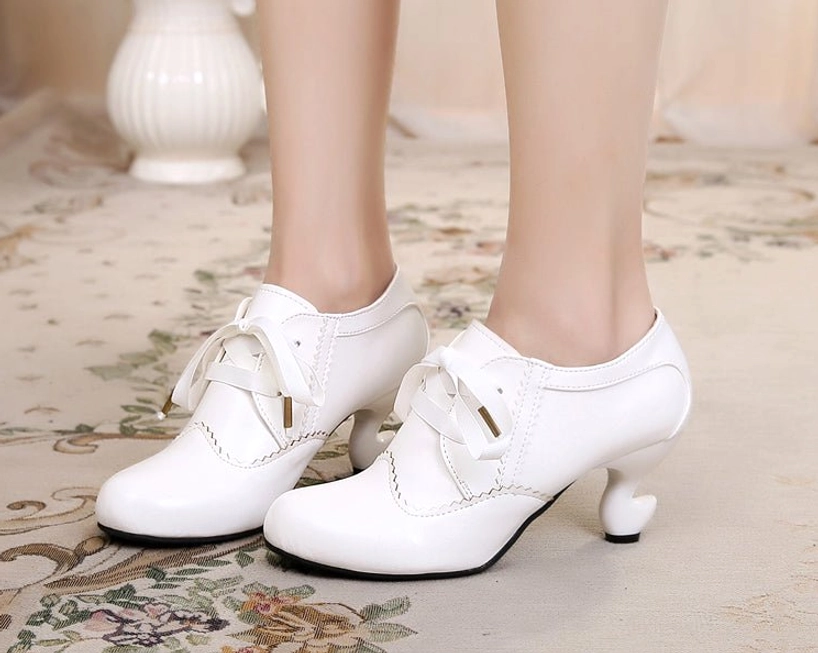Pure white retro lace-up Lolita high heel shoes with bright white finish, scalloped stitching details, curved spool heel, and ribbon lace ties with metal aglets on floral carpet