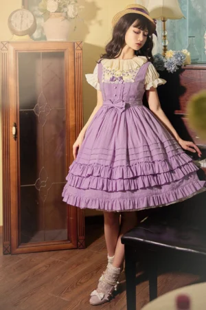 Purple embroidered cotton summer lolita JSK dress with tiered ruffle skirt, lace neck trim, waist bow decoration, and inner blouse in vintage indoor setting