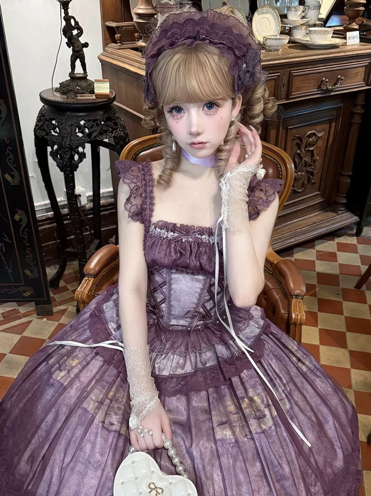Purple classic lolita jumper skirt dress with ruffled shoulder straps, lace-decorated fishbone bodice, and full circle skirt, sitting pose in vintage study room