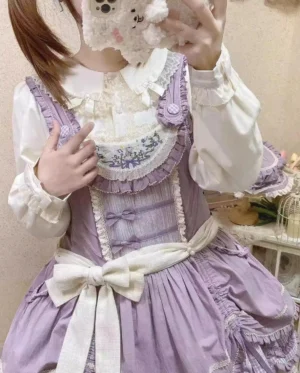 Purple Lolita ensemble with white Peter Pan collar blouse, embroidered lace neckline, large satin bow waist sash, and tiered ruffled skirt hem in vintage dollhouse interior