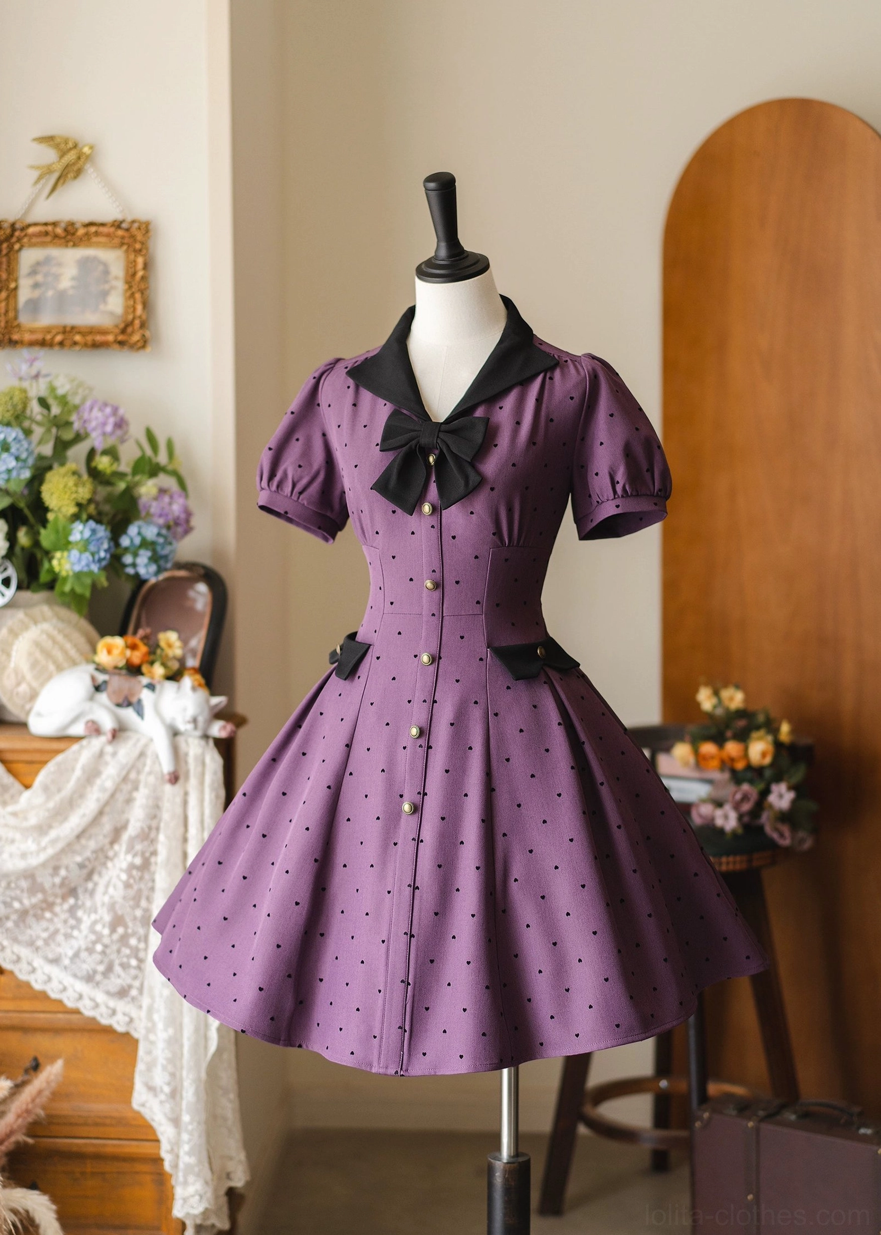 Purple polka-dot classic lolita OP dress front view on mannequin with black contrast collar removable bow puff sleeves and flocked dot embellishments vintage indoor decor setting