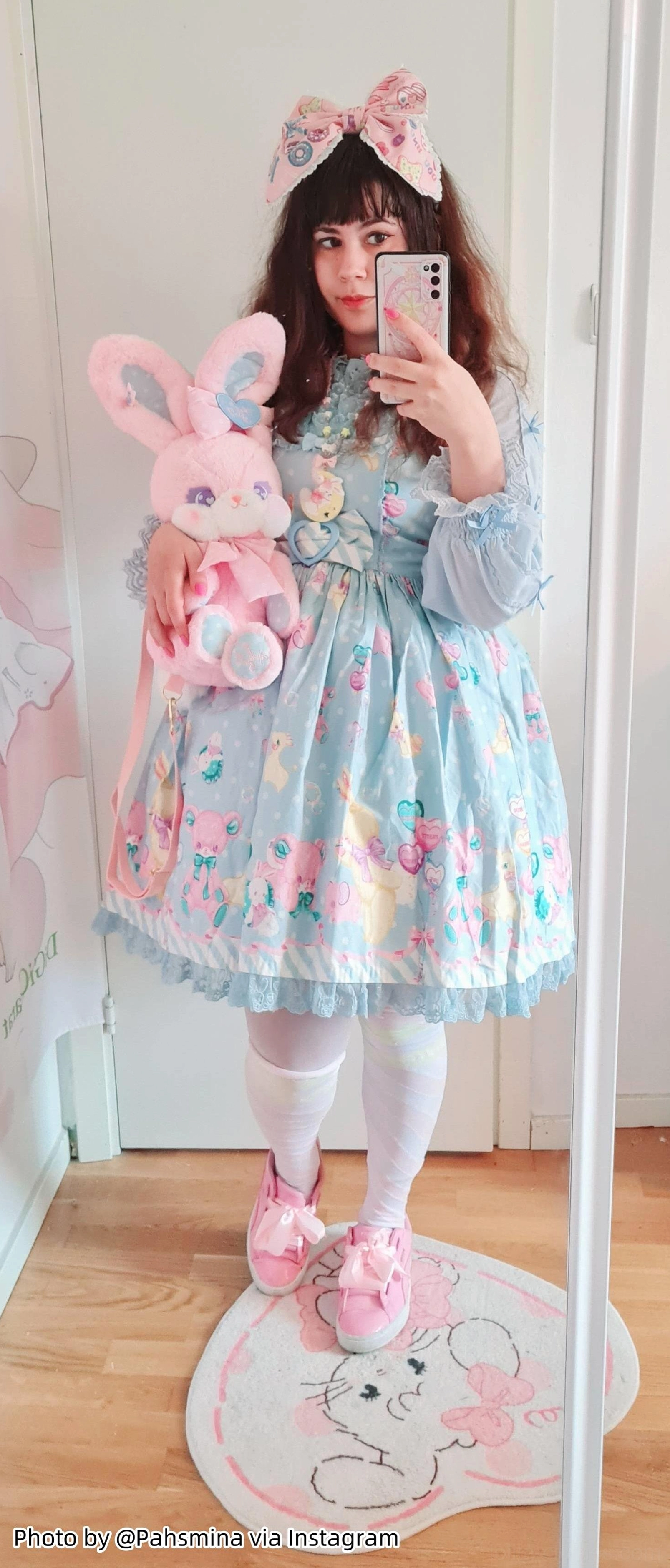 Lolita model full-length mirror selfie holding pink plush rabbit, wearing blue printed dress with rainbow petticoat underskirt, white stockings, pink bow clip, and pink loafers