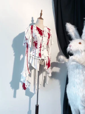 Blood-stained red Ouji lolita trailing blouse with asymmetrical ruffled hem displayed on dress mannequin, showcasing crimson splash design on white satin fabric against black backdrop