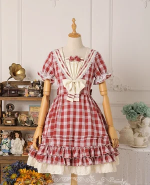Red gingham sailor lolita OP dress with cream sailor collar and bow, short puff sleeves, ruffled hemline with white underlayer, displayed on vintage dress mannequin in retro studio setting